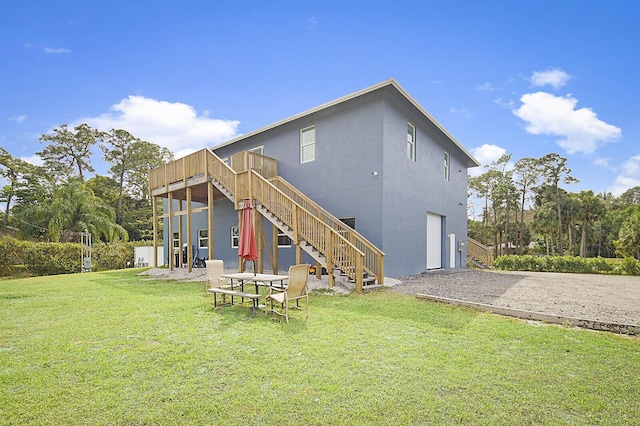 back of property featuring driveway, a yard, stairs, a garage, and a deck