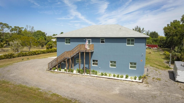 back of property with a wooden deck, driveway, and stairs