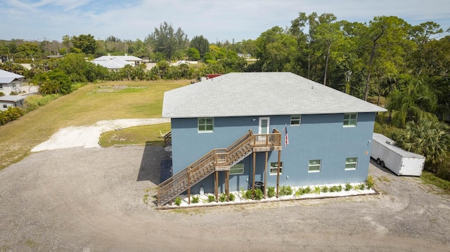 back of property featuring a lawn, driveway, and stairs