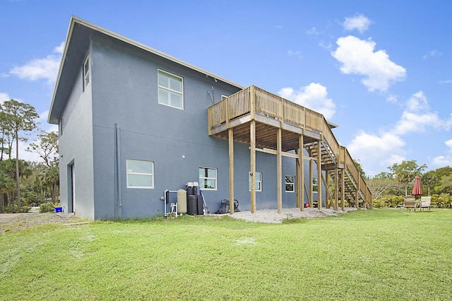 back of property with stairway, a yard, a wooden deck, and stucco siding