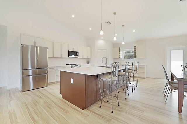 kitchen featuring a large island, appliances with stainless steel finishes, a breakfast bar area, white cabinets, and light countertops