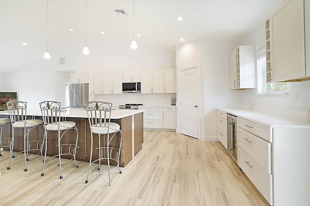 13327 Marcella Blvd, Loxahatchee Groves, FL 33470 - kitchen with a breakfast bar area, light wood-type flooring, visible vents, appliances with stainless steel finishes, and wine cooler