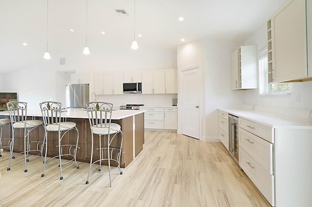 kitchen with visible vents, beverage cooler, a kitchen breakfast bar, appliances with stainless steel finishes, and light countertops