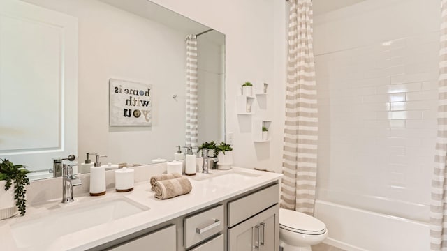 bathroom featuring toilet, double vanity, shower / bath combo with shower curtain, and a sink