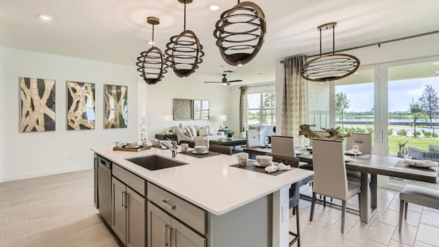 kitchen with light countertops, a sink, decorative light fixtures, and gray cabinetry