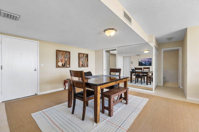 dining space with baseboards, visible vents, and a textured ceiling