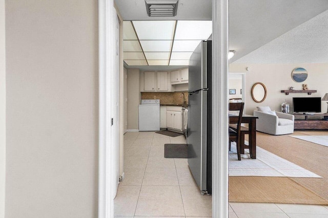 kitchen with washer / clothes dryer, light tile patterned flooring, freestanding refrigerator, decorative backsplash, and open floor plan