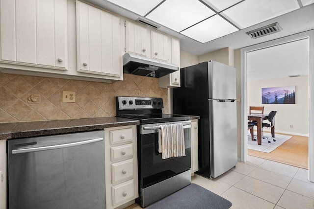 kitchen with dark countertops, visible vents, under cabinet range hood, light tile patterned floors, and stainless steel appliances