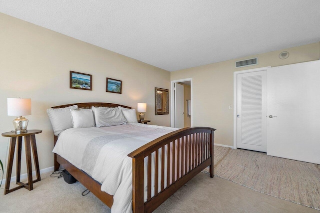 bedroom featuring light carpet, visible vents, a textured ceiling, and baseboards