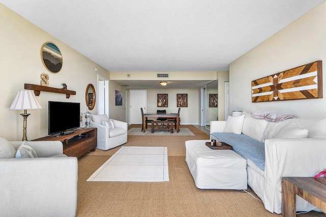 living area with carpet flooring, visible vents, and a textured ceiling