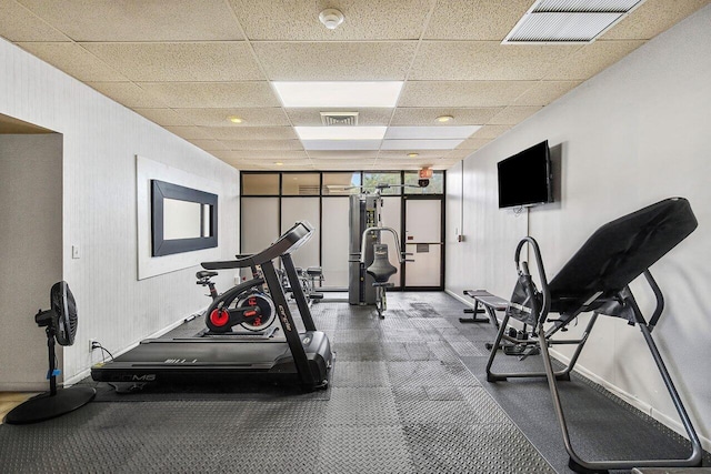 gym featuring visible vents, a paneled ceiling, and baseboards