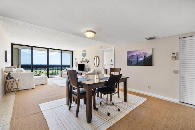 dining space featuring visible vents, expansive windows, a textured ceiling, light tile patterned floors, and baseboards