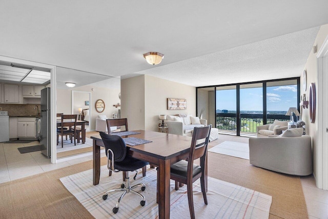 dining room featuring light tile patterned floors, washer / clothes dryer, a textured ceiling, and floor to ceiling windows