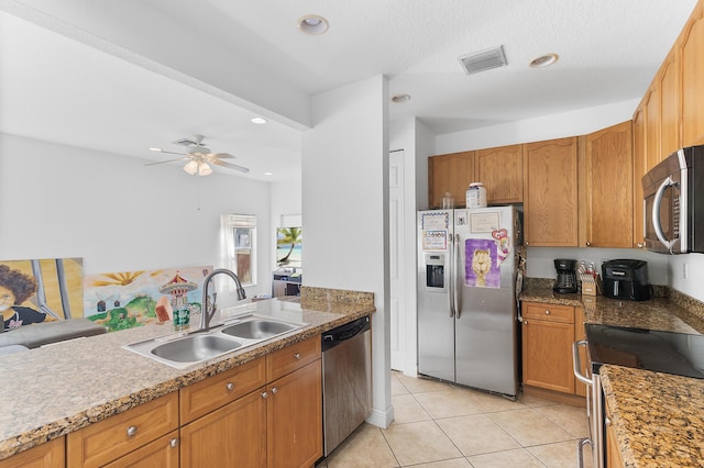 kitchen with visible vents, brown cabinetry, light tile patterned flooring, stainless steel appliances, and a sink