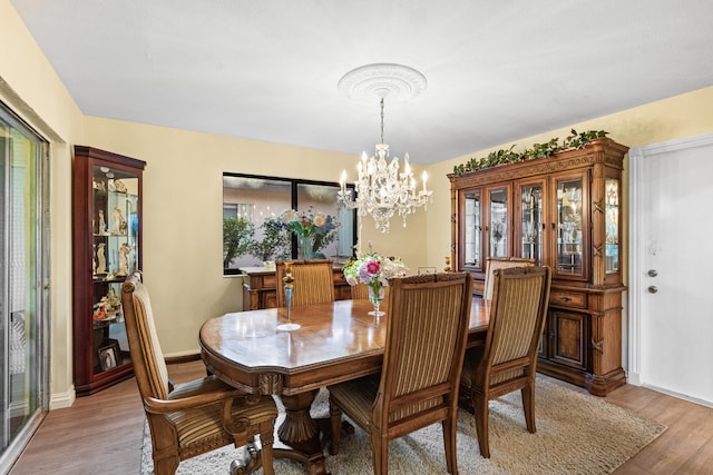 dining area featuring a wealth of natural light, light wood-type flooring, baseboards, and a chandelier