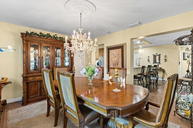 dining area with visible vents, baseboards, light wood-type flooring, and an inviting chandelier