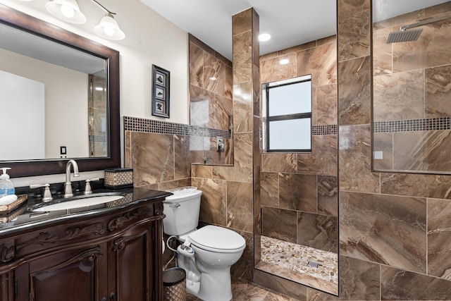 bathroom with tile walls, walk in shower, vanity, and toilet