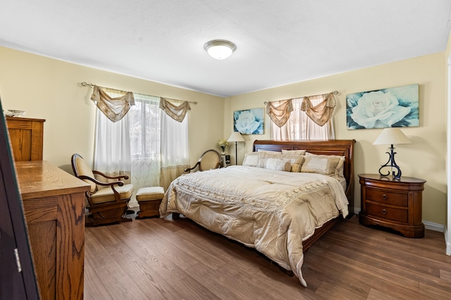 bedroom featuring baseboards and dark wood-style flooring