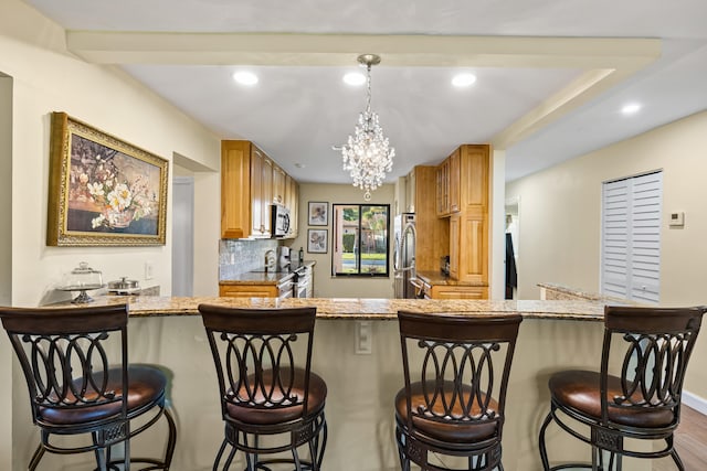 kitchen with a breakfast bar area, recessed lighting, stainless steel appliances, decorative backsplash, and hanging light fixtures