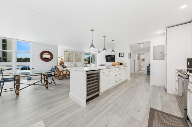 kitchen with beverage cooler, stainless steel electric range, light countertops, white cabinets, and pendant lighting