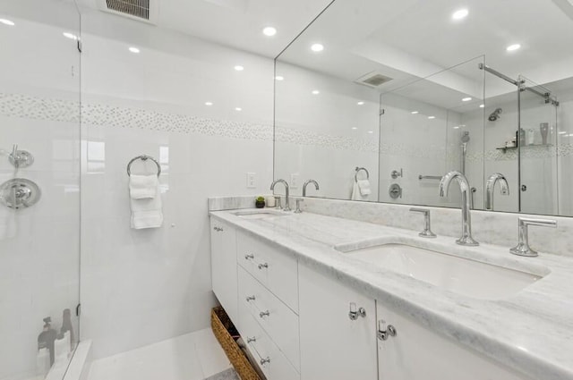 full bath featuring double vanity, visible vents, a shower stall, and a sink