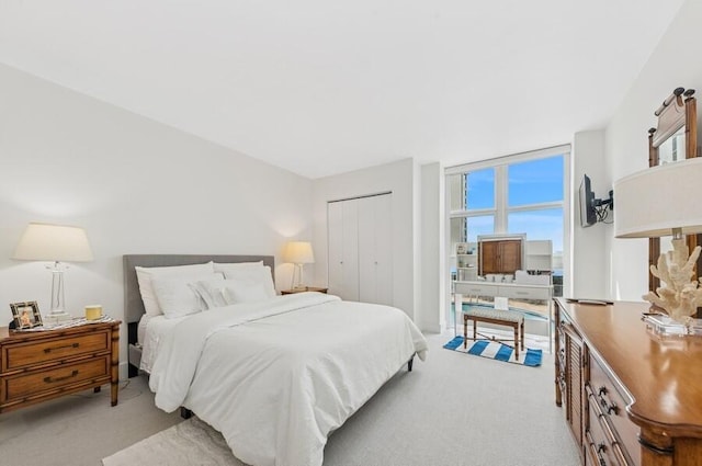 bedroom with floor to ceiling windows, a closet, and light carpet