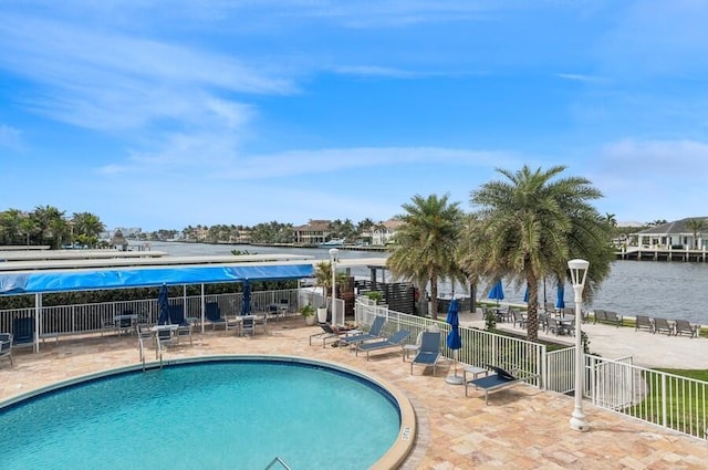 community pool featuring a patio, fence, and a water view