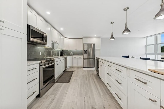 kitchen featuring decorative backsplash, light wood-style floors, appliances with stainless steel finishes, and white cabinetry