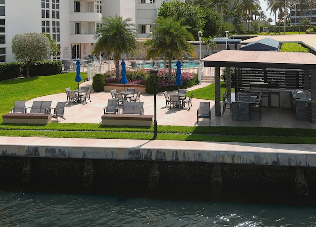 view of property's community featuring a patio area, a water view, and fence