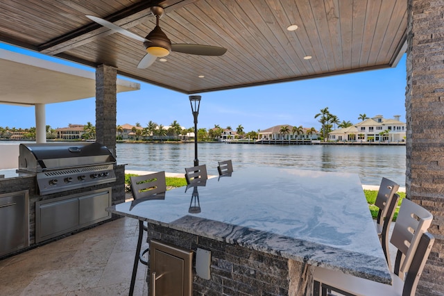 view of patio / terrace with an outdoor kitchen, ceiling fan, a water view, and a grill