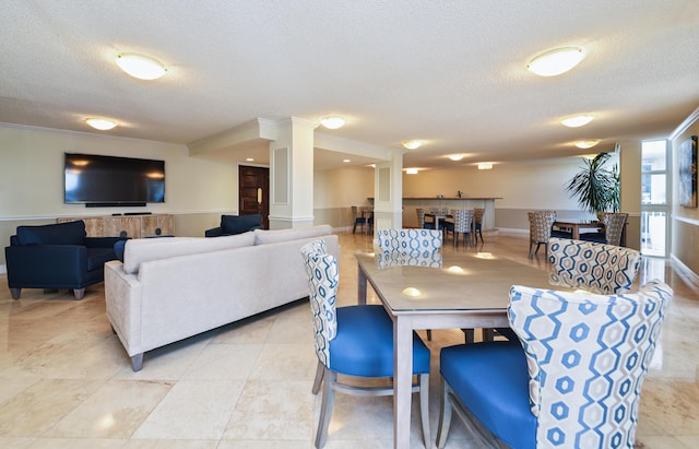 dining space with light tile patterned floors, decorative columns, a textured ceiling, and crown molding