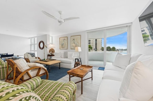 living room featuring light wood-type flooring, plenty of natural light, and a ceiling fan