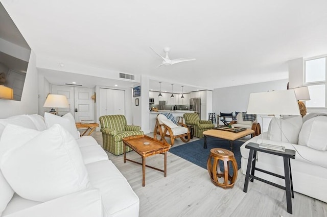 living area with light wood-type flooring, visible vents, and a ceiling fan