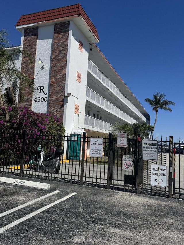 view of building exterior with fence and uncovered parking