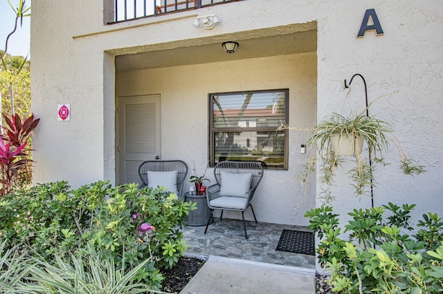 view of exterior entry with stucco siding and a patio