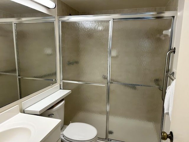 full bath with a shower with shower door, toilet, and vanity