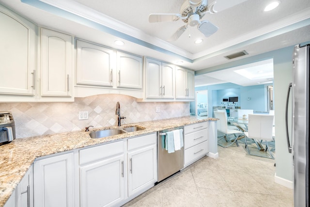 kitchen with tasteful backsplash, a tray ceiling, light tile patterned floors, appliances with stainless steel finishes, and a sink