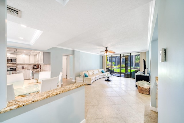 living room with visible vents, ornamental molding, a textured ceiling, and expansive windows