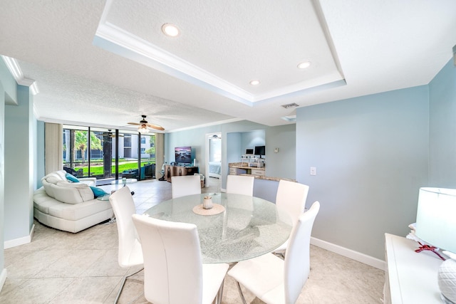 dining space featuring crown molding, a textured ceiling, a raised ceiling, and baseboards