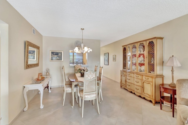 dining room with visible vents, baseboards, a notable chandelier, and a textured ceiling