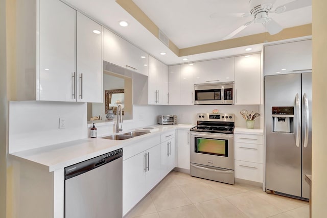 kitchen featuring light tile patterned floors, a sink, stainless steel appliances, light countertops, and white cabinetry