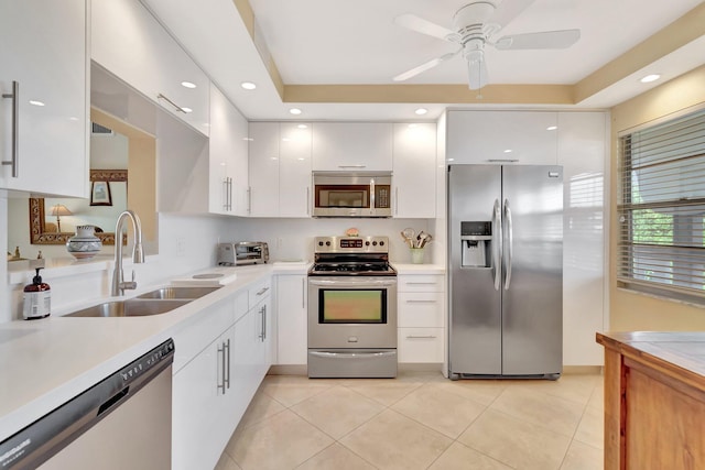 kitchen with a sink, appliances with stainless steel finishes, white cabinets, and light countertops