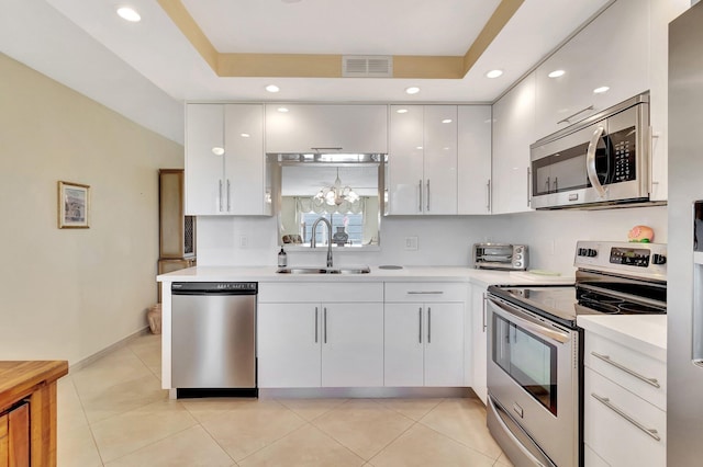 kitchen featuring visible vents, light countertops, white cabinets, stainless steel appliances, and a sink