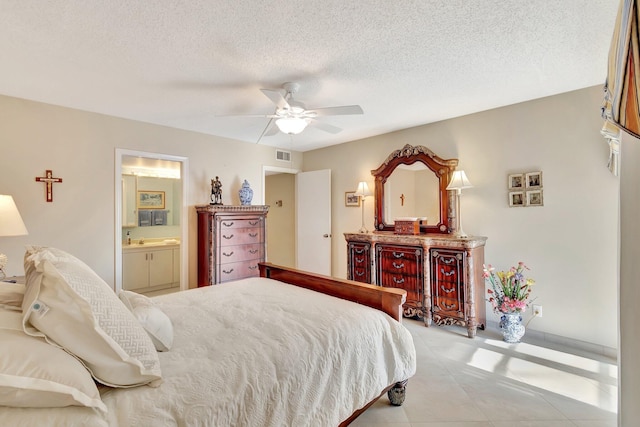 bedroom with ensuite bath, visible vents, a textured ceiling, and a ceiling fan