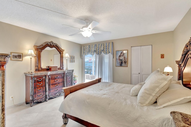 bedroom with ceiling fan, light tile patterned floors, a closet, and a textured ceiling