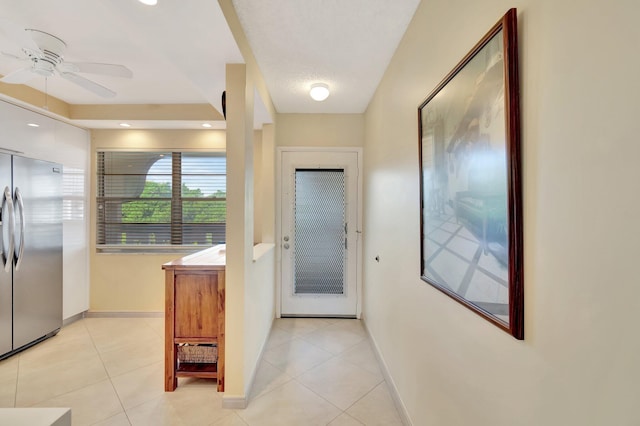 entryway with light tile patterned floors, a ceiling fan, and baseboards