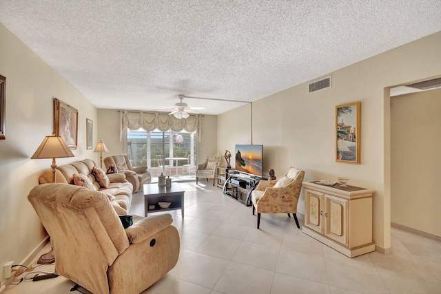 living area with light tile patterned floors, a ceiling fan, baseboards, visible vents, and a textured ceiling