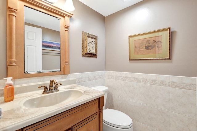 bathroom featuring vanity, tile walls, toilet, and a wainscoted wall