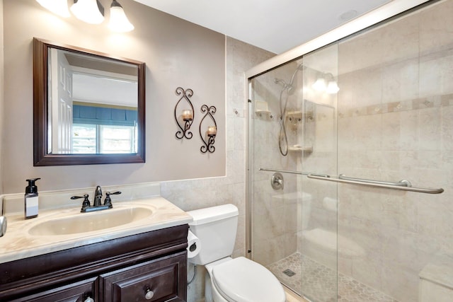 full bathroom featuring vanity, a shower stall, toilet, and tile walls