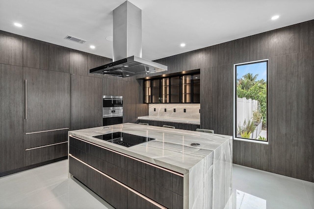 kitchen with visible vents, a large island, glass insert cabinets, black electric cooktop, and island range hood